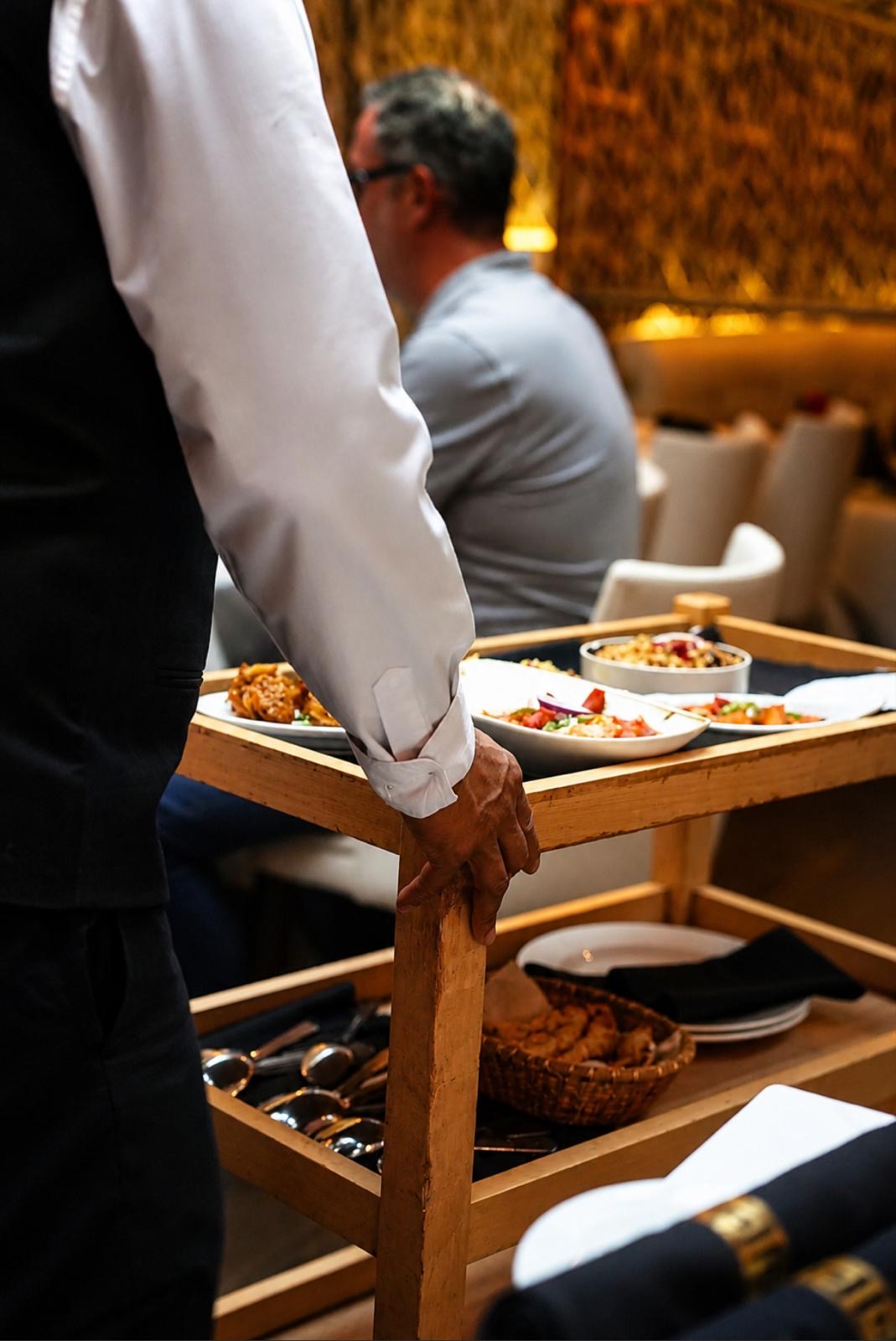 A waiter presenting dishes beside the table